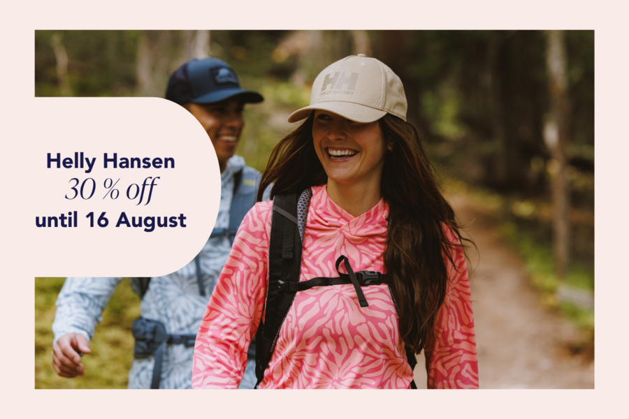Two hikers on a forest trail wearing Helly Hansen outdoor clothing.