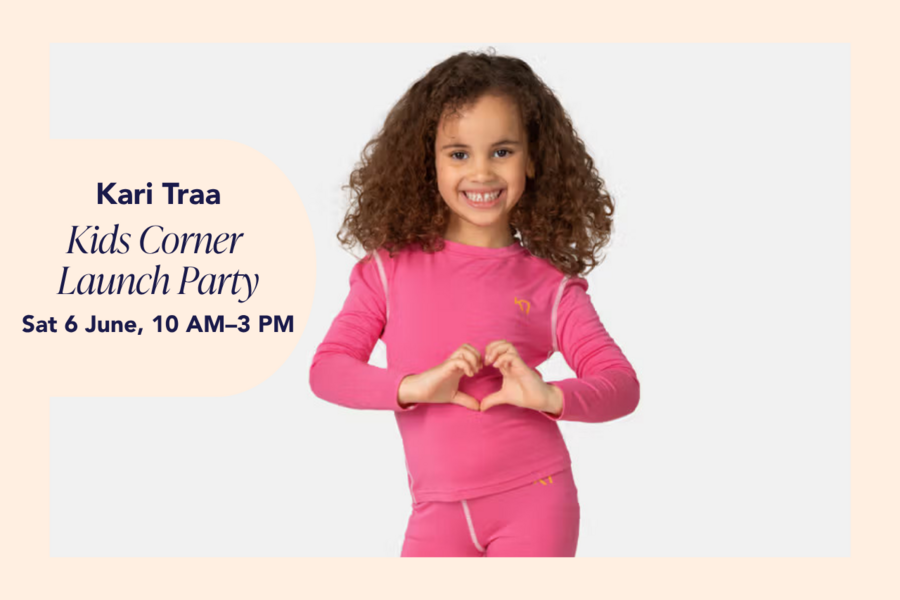 A curly-haired girl wearing a pink Kari Traa base layer set and making a heart shape with her hands.