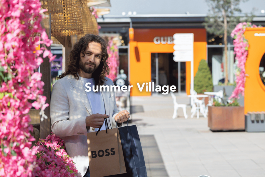 A man with shopping bags in Helsinki Outlet’s summer-decorated Central Square