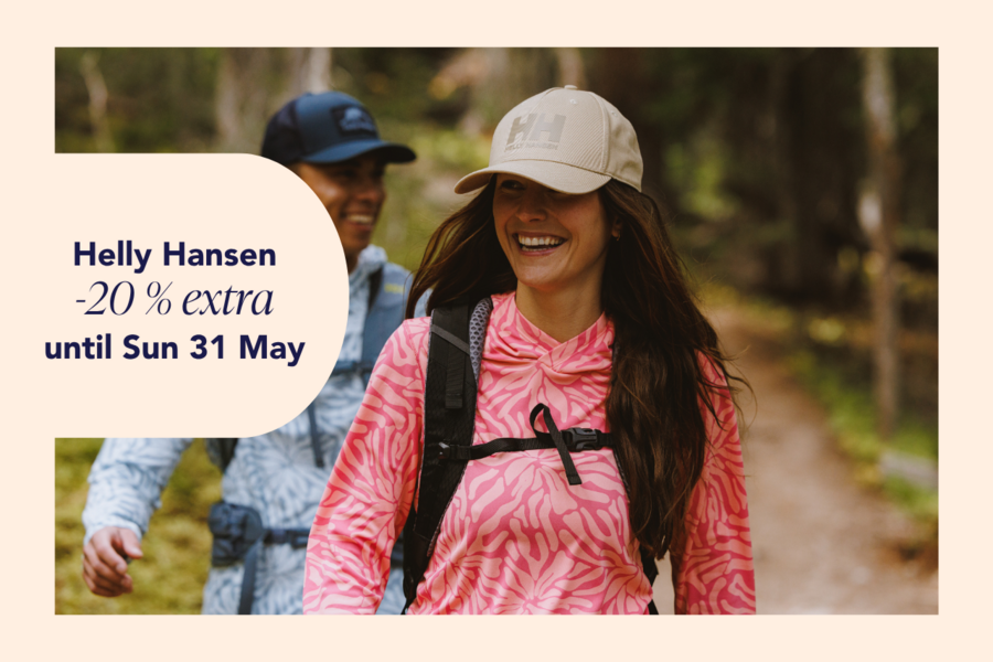 A man and a woman hiking in the forest, wearing Helly Hansen clothing and caps