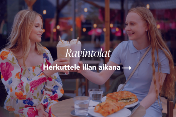 Kaksi tyttöä ostoskylän kahvilan terrasilla kesäiltana