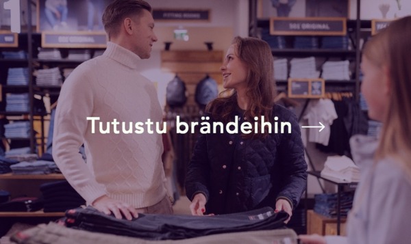 Mies ja nainen farkkuostoksilla ostoskylän myymälässä ja hymyilevät toisilleen