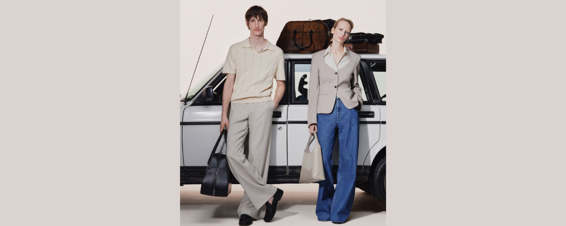 A man and a woman are leaning against a car with bags in their hands. There are also bags on the roof of the car.