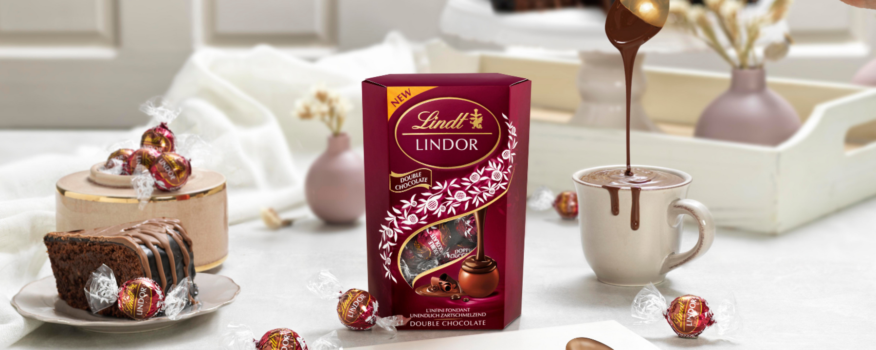 Lindt suklaapaketti pöydällä ja pala suklaakakkua suklaapaketin vieressä