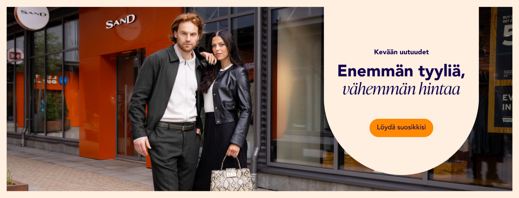 Nainen ja mies viettämässä päivää Helsinki Outletissa Sand myymälän edessä