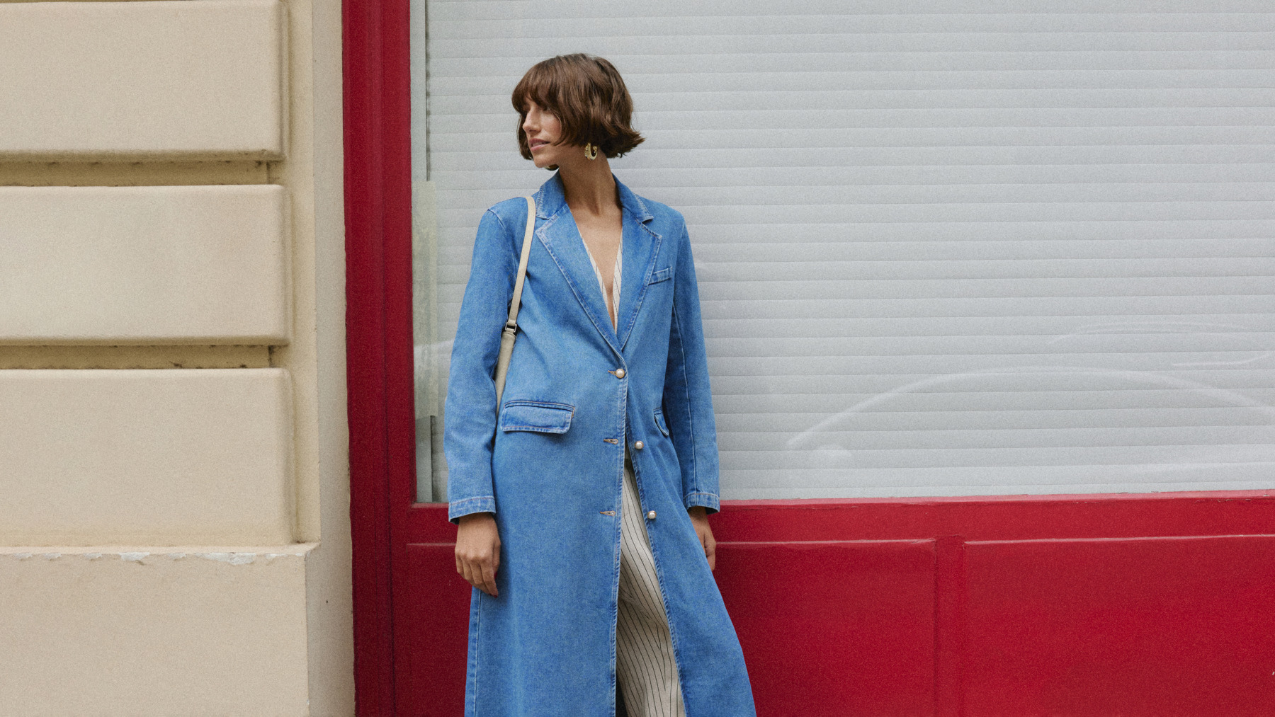 Women standing in front of a window wearing a long blue denim coat