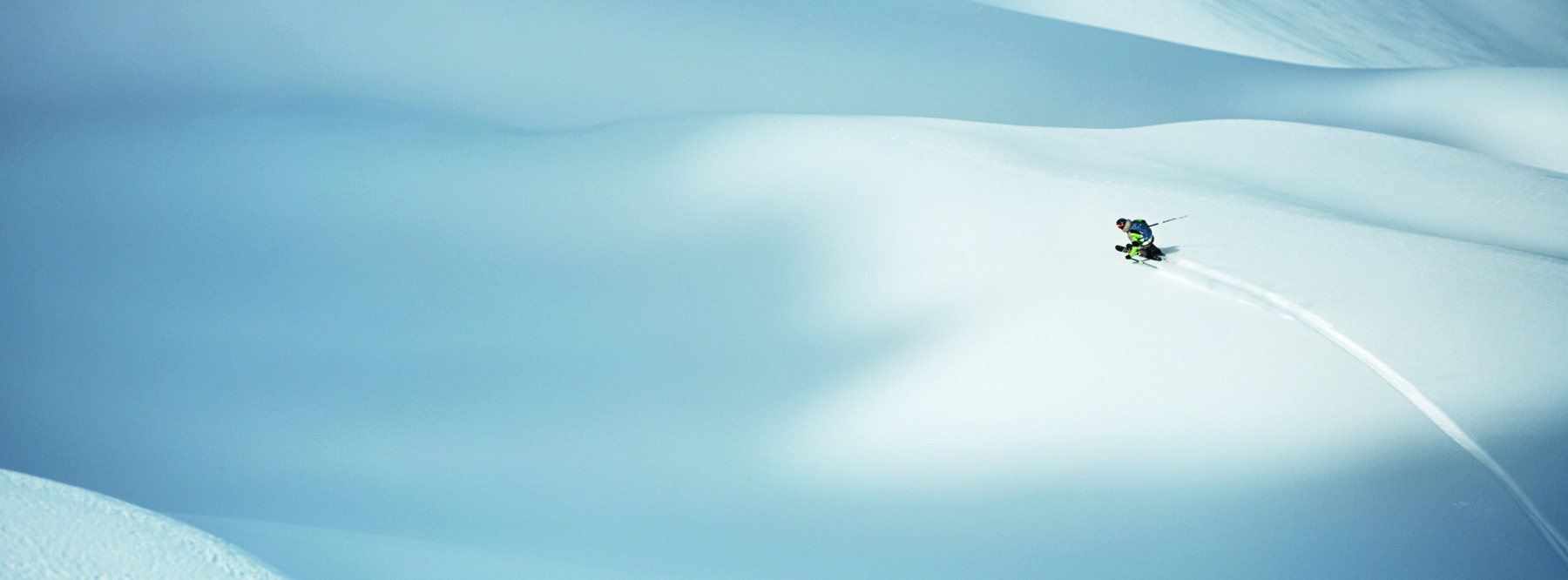 Hills ow snow. One person downhill skiiing in the distance.