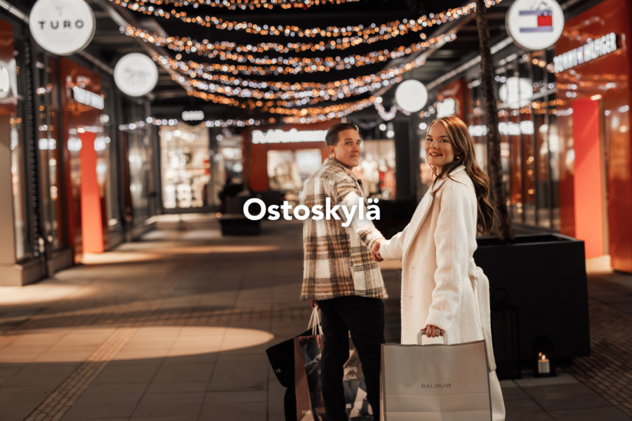 Pariskunta tekee ostoksia jouluvalojen loisteessa – ostoskylän taianomaisessa tunnelmassa.