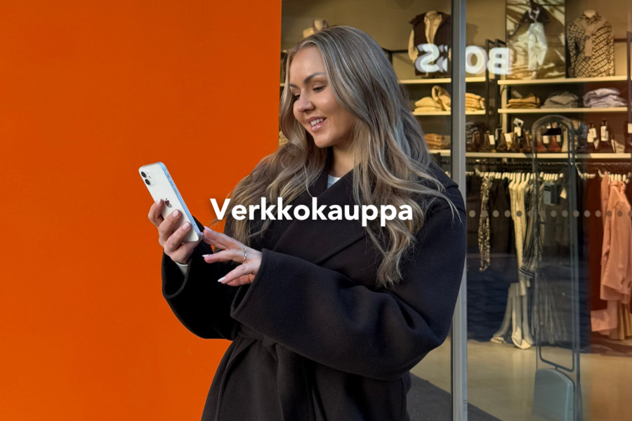 Nainen selaa puhelintaan Helsinki Outletissa