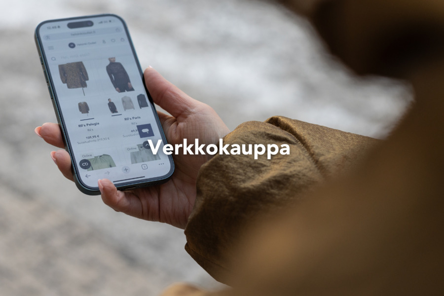 Puhelin kädessä ja näytöllä Helsinki Outletin verkkokauppa