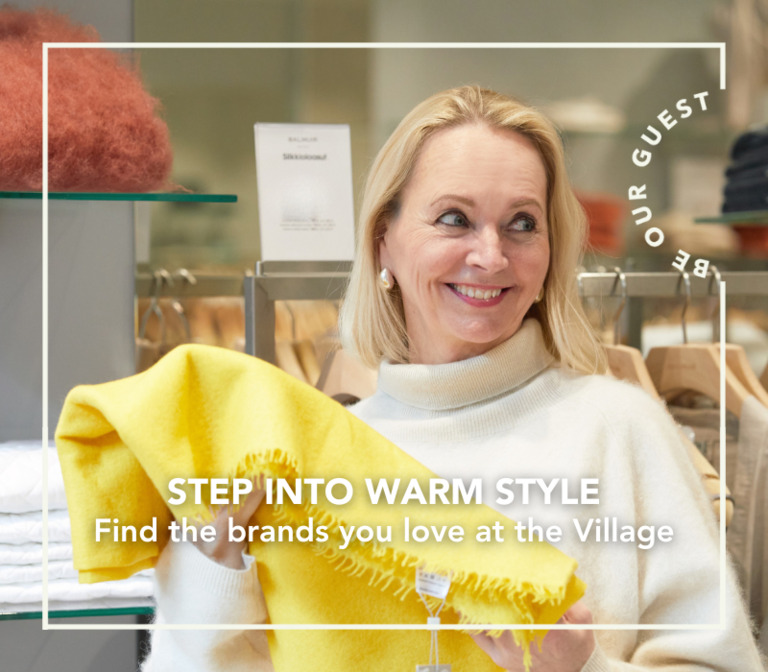 A woman is holding a beautiful yellow scarf in her hand