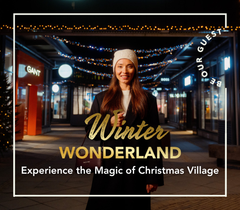 A woman visiting Helsinki Outlet on a late winter night, with Christmas lights behind her