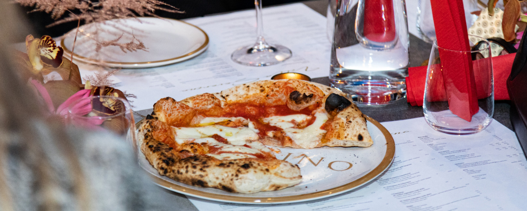 Pizza, menu ja viinilasi ravintolan pöydällä