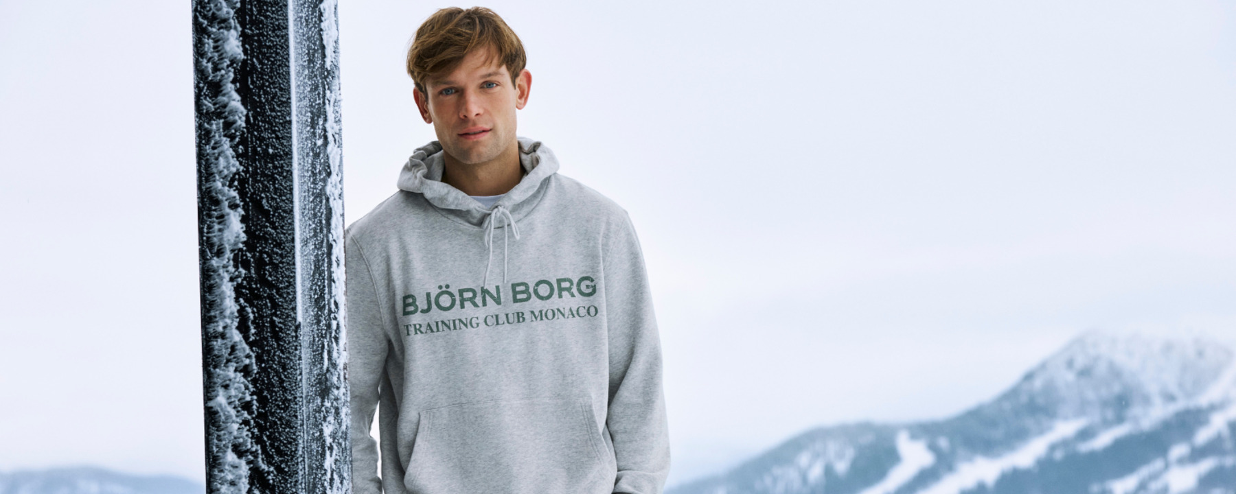 Mies, jolla on yllään harmaa Björn Borg -huppari ja taustalla luminen vuori