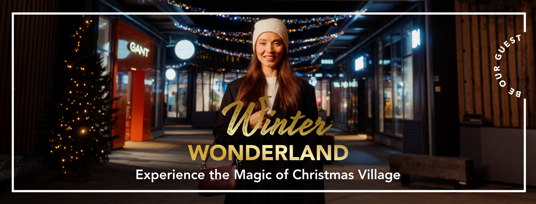 A woman visiting Helsinki Outlet on a late winter night, with Christmas lights behind her