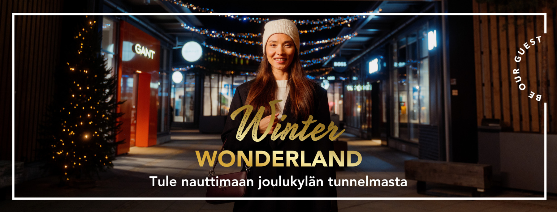 Nainen vierailemassa Helsinki Outletissa  talvi-iltana, jouluvalojen loistaessa hänen takanaan.